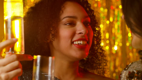 Close-Up-Of-Two-Women-In-Nightclub-Or-Bar-Celebrating-Drinking-Alcohol-With-Sparkling-Lights-2
